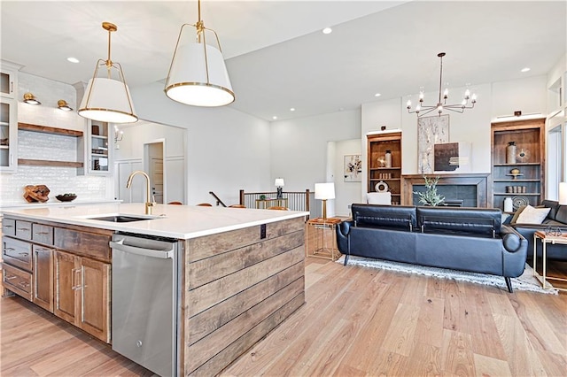 17404 Crystal St, Overland Park, KS 66221 - kitchen with stainless steel dishwasher, light wood-style flooring, an island with sink, backsplash, and a chandelier