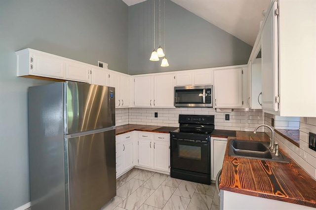 311 NE Bridge Pl, Blue Springs, MO 64014 - kitchen featuring appliances with stainless steel finishes, dark countertops, high vaulted ceiling, light marble finish floors, and white cabinetry