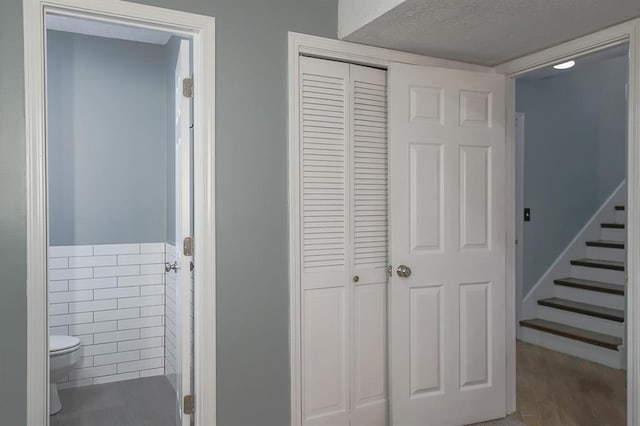 311 NE Bridge Pl, Blue Springs, MO 64014 - bathroom with a closet, tile walls, a wainscoted wall, and a textured ceiling