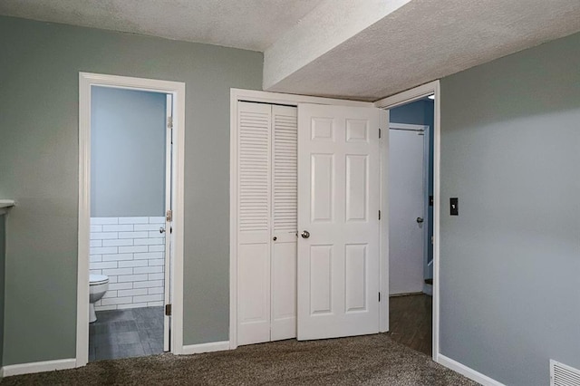 311 NE Bridge Pl, Blue Springs, MO 64014 - unfurnished bedroom featuring carpet floors, ensuite bathroom, a textured ceiling, and a closet