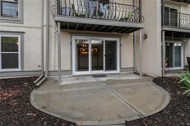 10734 Glenwood St Unit A, Overland Park, KS 66211 - view of exterior entry with a balcony, stucco siding, and a patio area