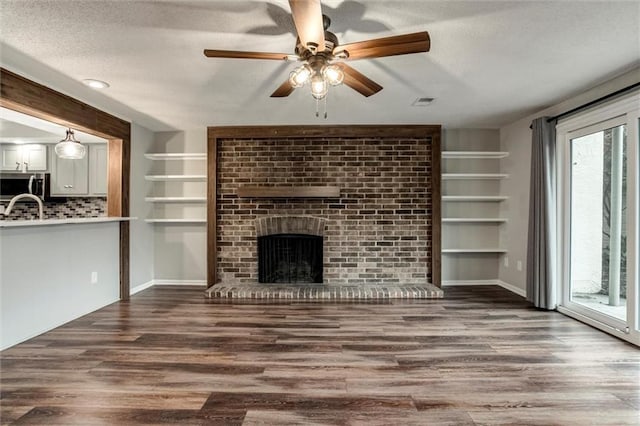 10734 Glenwood St Unit A, Overland Park, KS 66211 - unfurnished living room featuring a textured ceiling, a ceiling fan, wood finished floors, and a brick fireplace