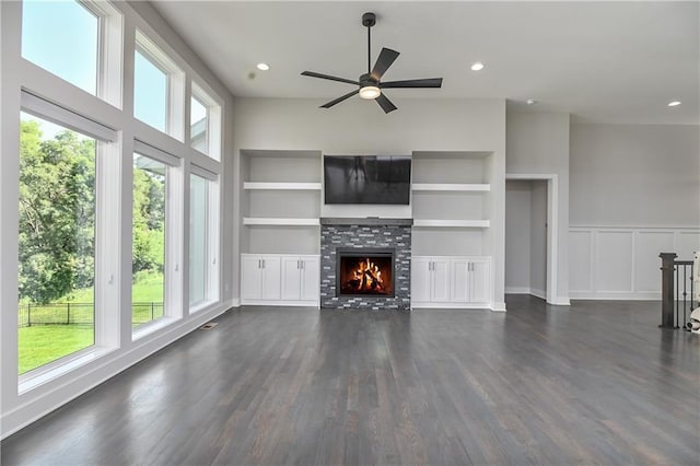 14500 Aurora Ln, Basehor, KS 66007 - unfurnished living room featuring dark wood-type flooring, ceiling fan, a lit fireplace, built in shelves, and recessed lighting