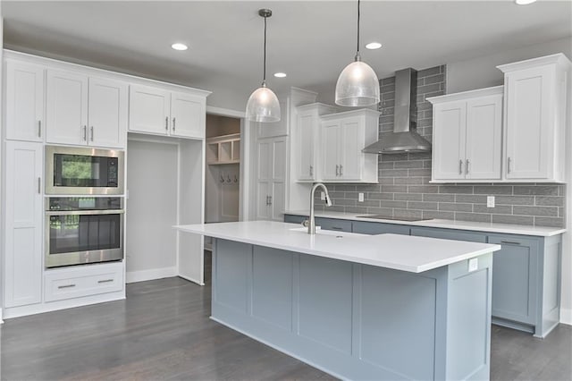 14500 Aurora Ln, Basehor, KS 66007 - kitchen with stainless steel appliances, wall chimney range hood, tasteful backsplash, a center island with sink, and recessed lighting
