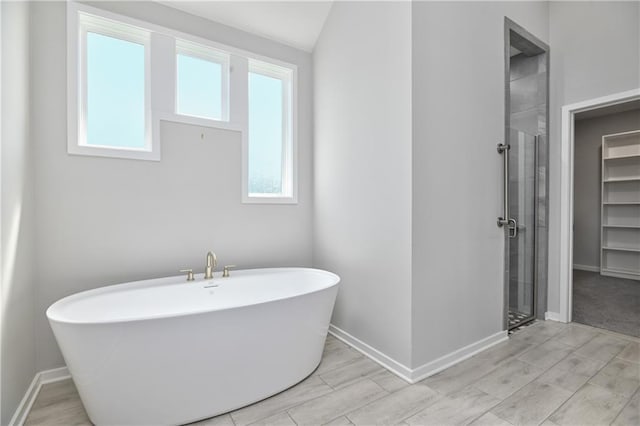 14500 Aurora Ln, Basehor, KS 66007 - bathroom with a soaking tub, a stall shower, a spacious closet, and wood finished floors