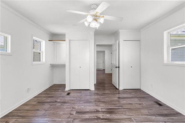 5706 Beverly Ave, Mission, KS 66202 - unfurnished bedroom featuring multiple windows, dark wood-style floors, ornamental molding, and two closets