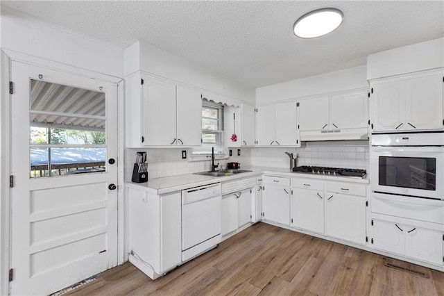 2206 N 73rd Ter, Kansas City, KS 66109 - kitchen featuring white appliances, healthy amount of natural light, under cabinet range hood, white cabinetry, and a textured ceiling