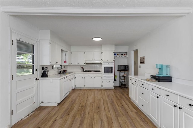 2206 N 73rd Ter, Kansas City, KS 66109 - kitchen with oven, light wood-style flooring, and white cabinetry