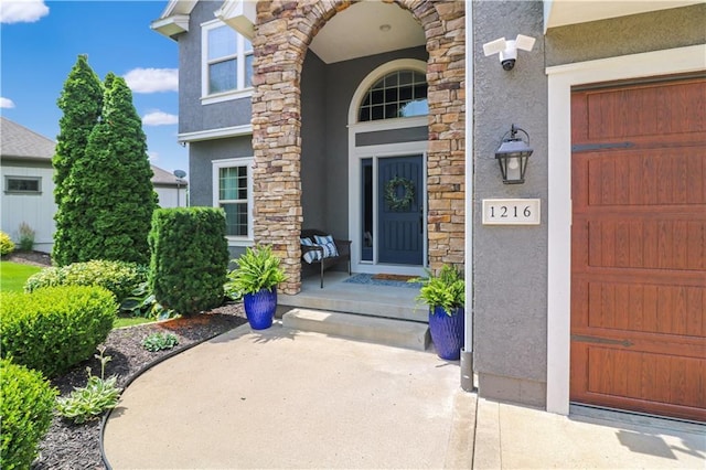 1216 Hillmann Ln, Warrensburg, MO 64093 - property entrance featuring stucco siding, stone siding, and a garage