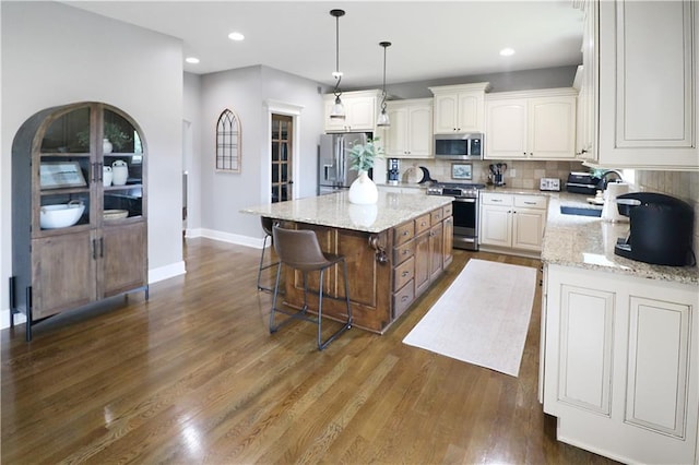 1216 Hillmann Ln, Warrensburg, MO 64093 - kitchen with appliances with stainless steel finishes, a kitchen island, backsplash, light stone countertops, and recessed lighting
