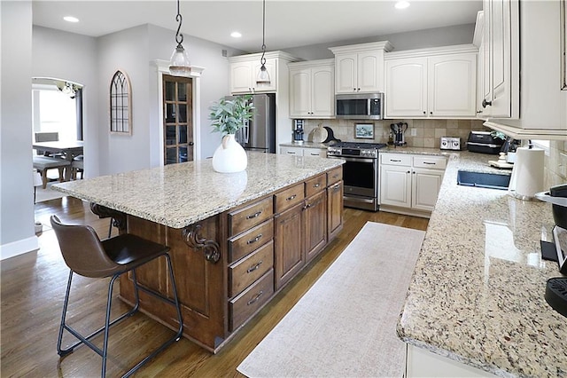 1216 Hillmann Ln, Warrensburg, MO 64093 - kitchen featuring stainless steel appliances, a kitchen island, white cabinets, dark wood-style flooring, and backsplash