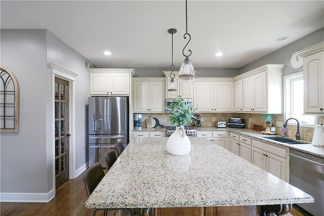 1216 Hillmann Ln, Warrensburg, MO 64093 - kitchen with appliances with stainless steel finishes, backsplash, dark wood finished floors, a kitchen island, and hanging light fixtures