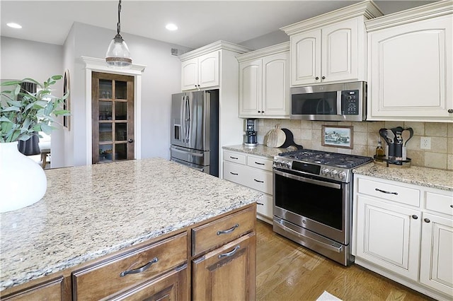 1216 Hillmann Ln, Warrensburg, MO 64093 - kitchen featuring stainless steel appliances, wood finished floors, backsplash, decorative light fixtures, and light stone counters
