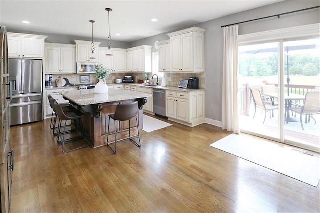 1216 Hillmann Ln, Warrensburg, MO 64093 - kitchen with stainless steel appliances, decorative backsplash, a breakfast bar area, white cabinets, and a kitchen island