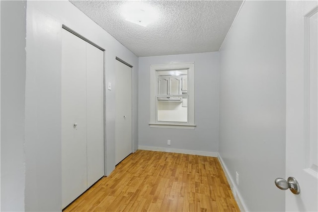 814 S Saville St, Independence, MO 64052 - unfurnished bedroom with two closets, a textured ceiling, and light wood-style floors