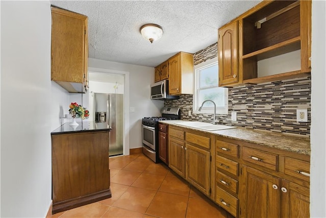 814 S Saville St, Independence, MO 64052 - kitchen featuring appliances with stainless steel finishes, backsplash, light tile patterned flooring, brown cabinetry, and a textured ceiling