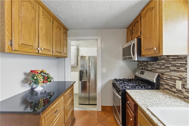 814 S Saville St, Independence, MO 64052 - kitchen featuring appliances with stainless steel finishes, tasteful backsplash, light tile patterned floors, and brown cabinetry