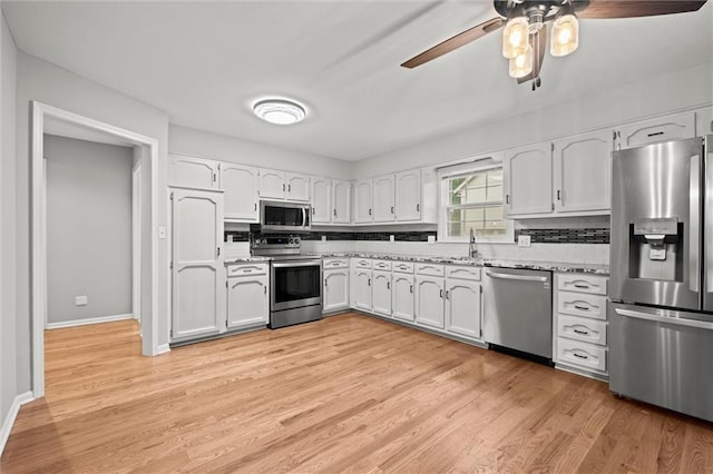 12343 Pinehurst Dr, Kansas City, KS 66109 - kitchen with stainless steel appliances, a ceiling fan, white cabinetry, light wood-type flooring, and backsplash