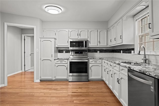 12343 Pinehurst Dr, Kansas City, KS 66109 - kitchen with appliances with stainless steel finishes, white cabinets, decorative backsplash, and light wood finished floors