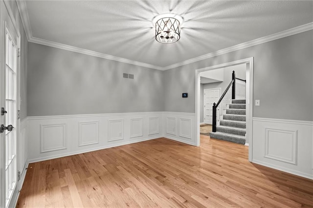 12343 Pinehurst Dr, Kansas City, KS 66109 - spare room with stairway, light wood finished floors, wainscoting, crown molding, and a chandelier