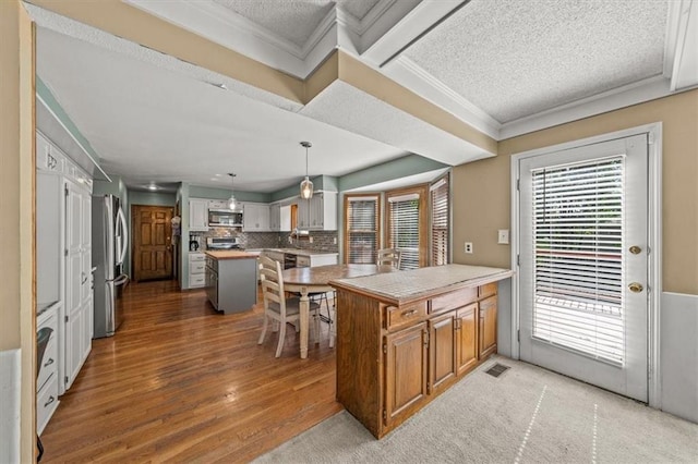 10601 Reeder St, Overland Park, KS 66214 - kitchen with appliances with stainless steel finishes, wood finished floors, a textured ceiling, light countertops, and tasteful backsplash