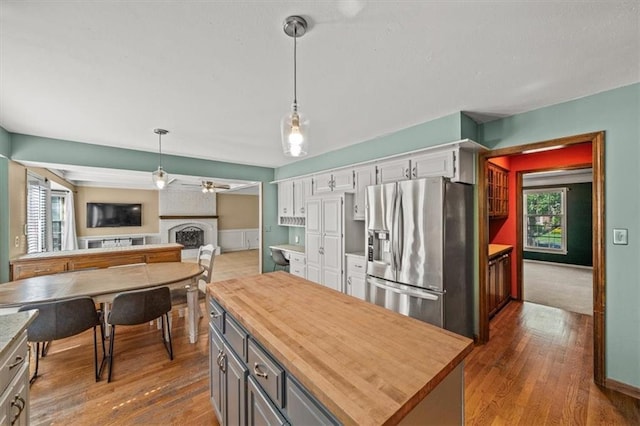 10601 Reeder St, Overland Park, KS 66214 - kitchen with stainless steel fridge with ice dispenser, butcher block countertops, ceiling fan, a fireplace, and pendant lighting