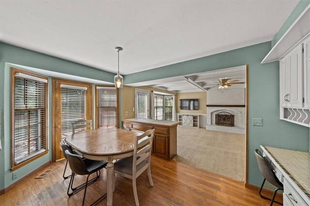 10601 Reeder St, Overland Park, KS 66214 - dining space with a fireplace, ceiling fan, light wood-type flooring, and beamed ceiling