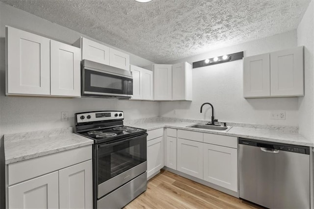 902 Twin Oaks Ter, Harrisonville, MO 64701 - kitchen with stainless steel appliances, a textured ceiling, light wood-style floors, white cabinets, and light stone countertops