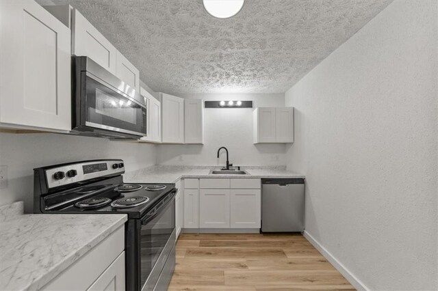 902 Twin Oaks Ter, Harrisonville, MO 64701 - kitchen with appliances with stainless steel finishes, a textured ceiling, light wood-type flooring, white cabinetry, and light countertops