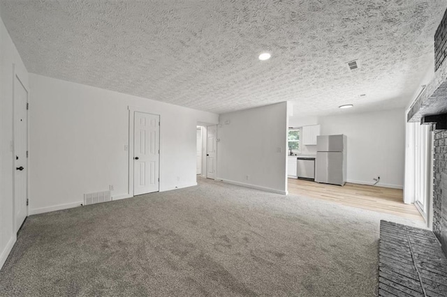 902 Twin Oaks Ter, Harrisonville, MO 64701 - unfurnished living room featuring light colored carpet, a fireplace, and a textured ceiling