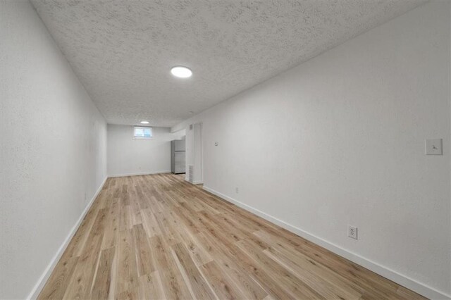 904 Twin Oaks Ter, Harrisonville, MO 64701 - below grade area with light wood finished floors, a textured ceiling, and freestanding refrigerator