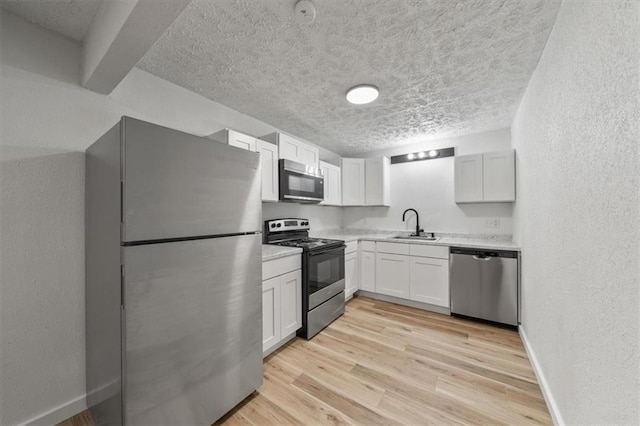 904 Twin Oaks Ter, Harrisonville, MO 64701 - kitchen featuring stainless steel appliances, a textured ceiling, light countertops, a textured wall, and white cabinets