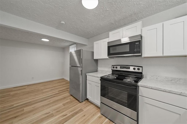 904 Twin Oaks Ter, Harrisonville, MO 64701 - kitchen featuring stainless steel appliances, a textured ceiling, light wood finished floors, white cabinetry, and light stone countertops