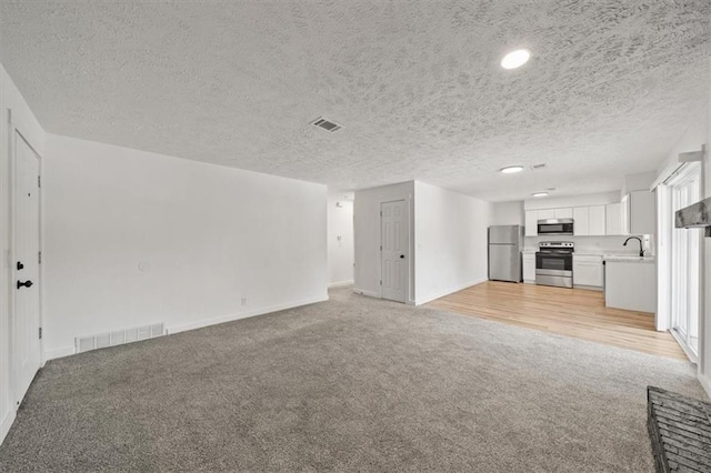 904 Twin Oaks Ter, Harrisonville, MO 64701 - unfurnished living room with light colored carpet, a textured ceiling, and recessed lighting
