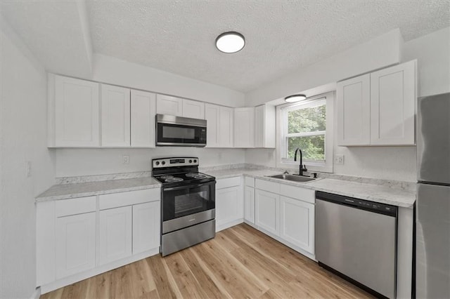 904 Twin Oaks Ter, Harrisonville, MO 64701 - kitchen with stainless steel appliances, a textured ceiling, white cabinets, and light countertops