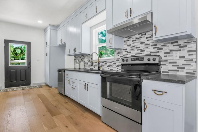 731 S Main St, Ottawa, KS 66067 - kitchen with appliances with stainless steel finishes, under cabinet range hood, dark countertops, light wood-style flooring, and recessed lighting