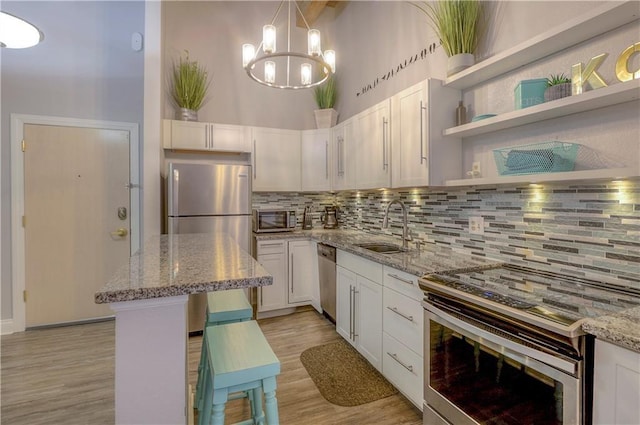 308 W 8th St Unit 420, Kansas City, MO 64105 - kitchen featuring appliances with stainless steel finishes, backsplash, light wood-type flooring, and light stone countertops