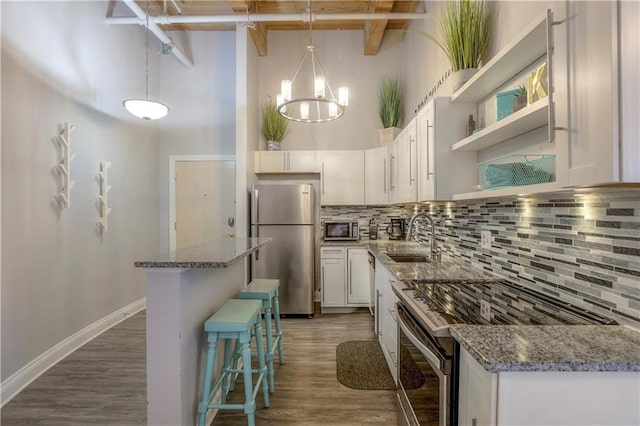 308 W 8th St Unit 420, Kansas City, MO 64105 - kitchen with appliances with stainless steel finishes, a high ceiling, dark wood finished floors, white cabinetry, and decorative backsplash