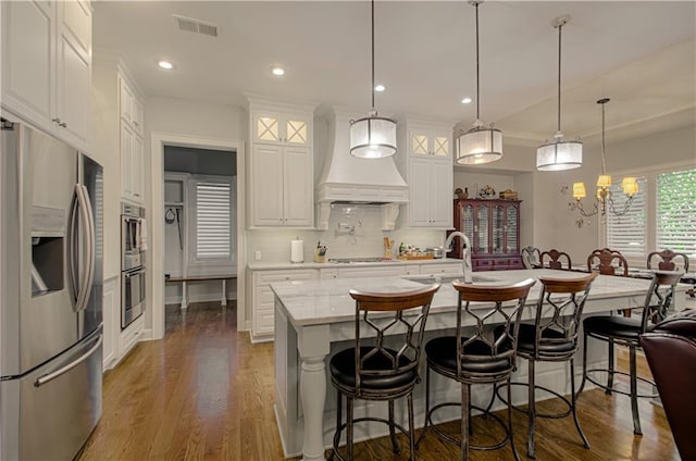 10423 W 168th Ter, Overland Park, KS 66221 - kitchen with stainless steel appliances, custom range hood, white cabinets, decorative backsplash, and wood finished floors