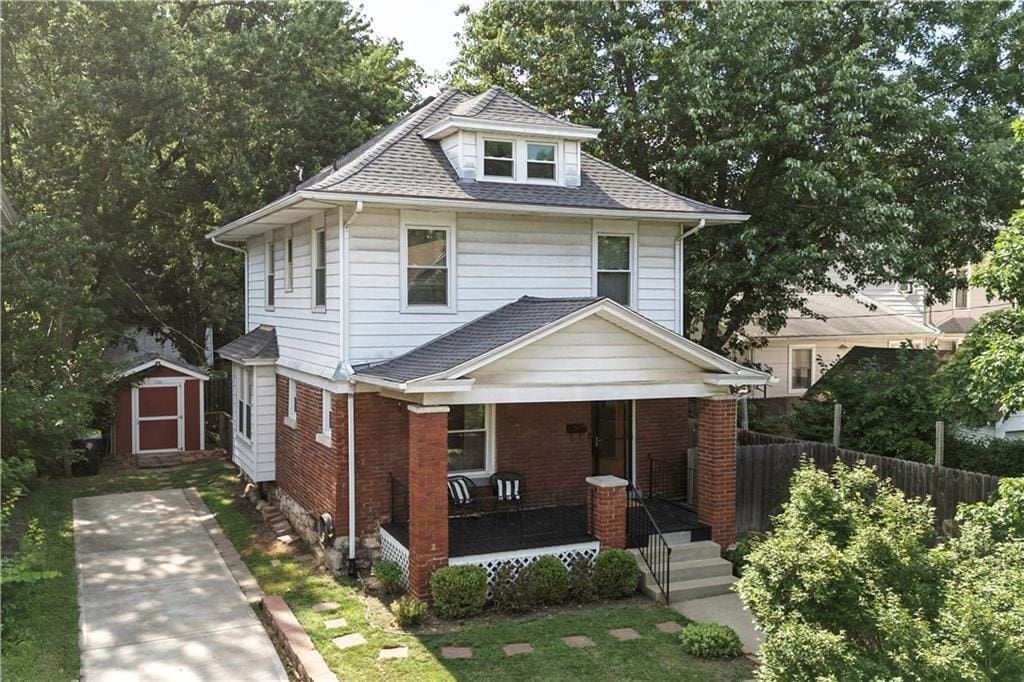 4008 Terrace St, Kansas City, MO 64111 - american foursquare style home with covered porch, a storage unit, roof with shingles, and brick siding
