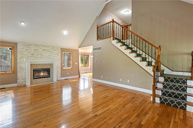 1125 S Mulberry St, Ottawa, KS 66067 - unfurnished living room featuring wood finished floors, stairway, high vaulted ceiling, a tiled fireplace, and recessed lighting