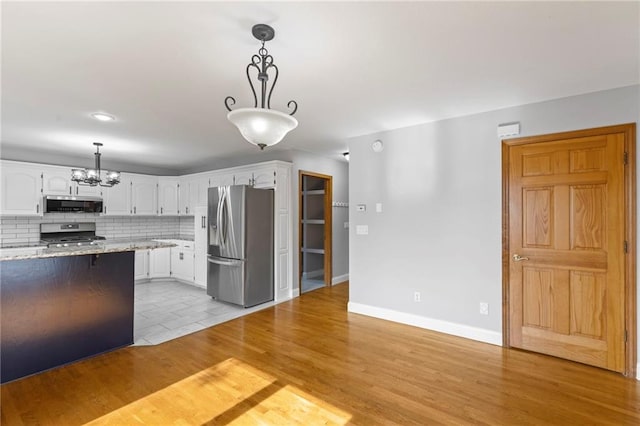 1125 S Mulberry St, Ottawa, KS 66067 - kitchen featuring stainless steel appliances, a chandelier, white cabinetry, backsplash, and light stone countertops