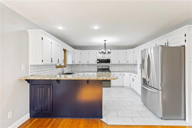 1125 S Mulberry St, Ottawa, KS 66067 - kitchen featuring stainless steel appliances, a peninsula, a chandelier, white cabinetry, and decorative backsplash