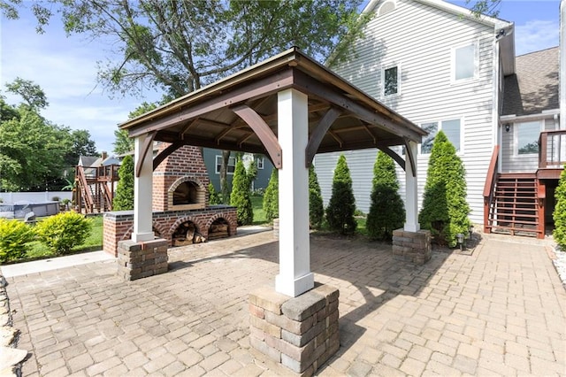 1125 S Mulberry St, Ottawa, KS 66067 - view of patio featuring an outdoor brick fireplace, a gazebo, stairway, and a wooden deck