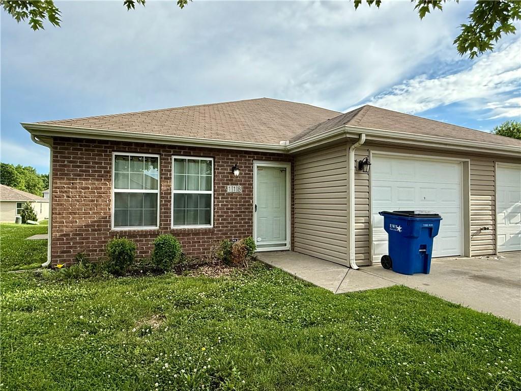 118 SW Rock Garden Ln, Lees Summit, MO 64064 - ranch-style house with brick siding, a front yard, a shingled roof, and a garage