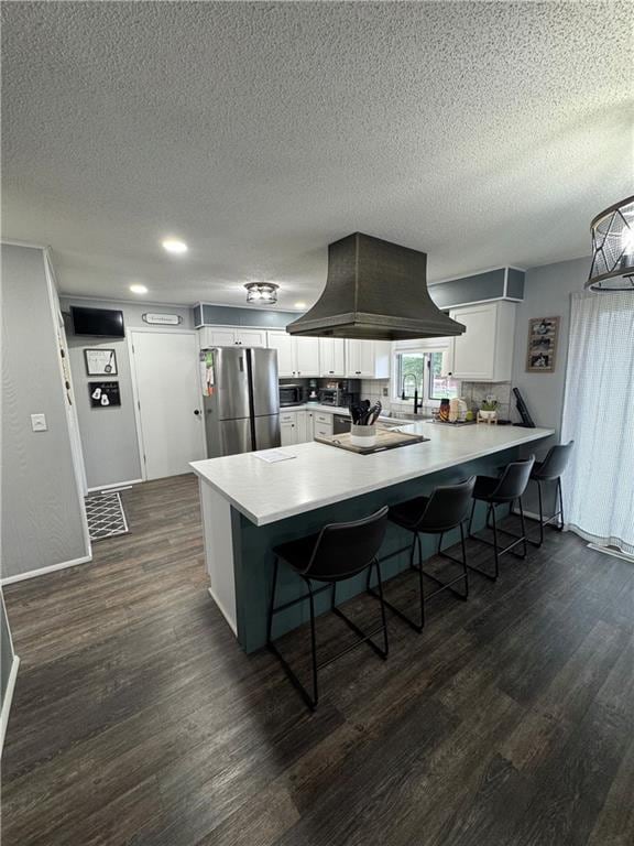 109 W 3rd St, Stanberry, MO 64489 - kitchen featuring freestanding refrigerator, a peninsula, island exhaust hood, a kitchen bar, and a textured ceiling