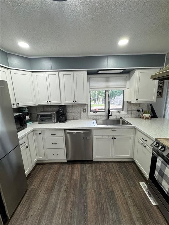 109 W 3rd St, Stanberry, MO 64489 - kitchen with stainless steel appliances, dark wood-type flooring, a textured ceiling, white cabinets, and light countertops