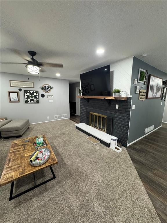 109 W 3rd St, Stanberry, MO 64489 - living area with a textured ceiling, a brick fireplace, ceiling fan, and dark wood-style flooring