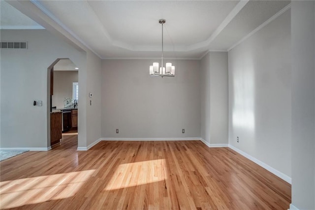 12546 Augusta Dr, Kansas City, KS 66109 - unfurnished room with arched walkways, light wood-style floors, a tray ceiling, a chandelier, and ornamental molding