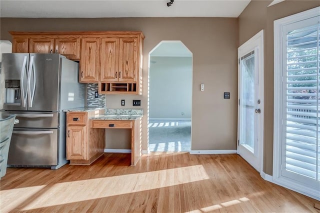 12546 Augusta Dr, Kansas City, KS 66109 - kitchen featuring stainless steel refrigerator with ice dispenser, light wood-style flooring, arched walkways, and open shelves